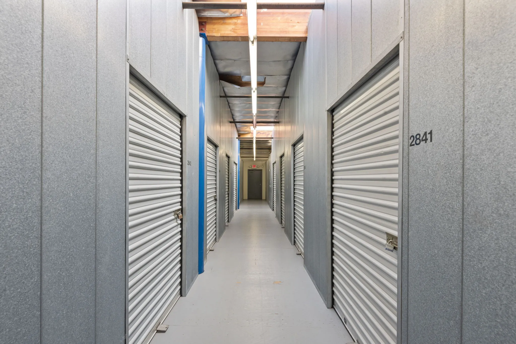 Well-lit interior corridor with secure storage unit doors at Spencer Street Self Storage.